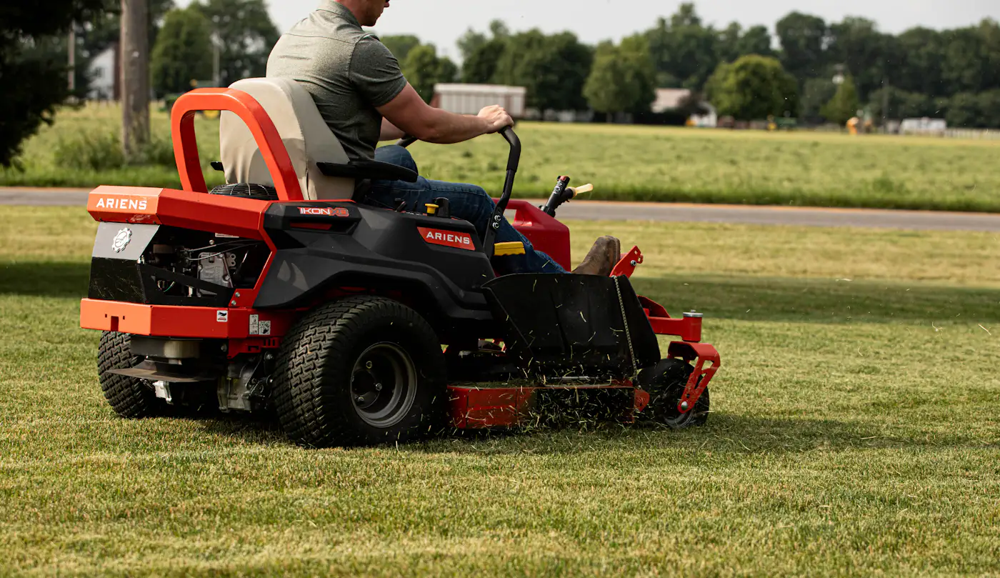 A crew member mowing a lawn with a riding mower
